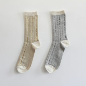 シャリ感のある綿麻クレープ糸で編立てた　薄地の靴下です。縦に流れるステッチは　雨垂れをイメージしてデザインしました。イエローとグレーの2色展開です。