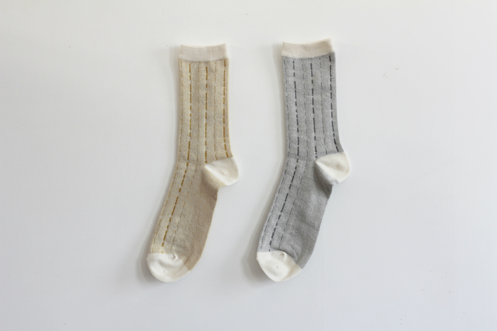 シャリ感のある綿麻クレープ糸で編立てた　薄地の靴下です。縦に流れるステッチは　雨垂れをイメージしてデザインしました。イエローとグレーの2色展開です。